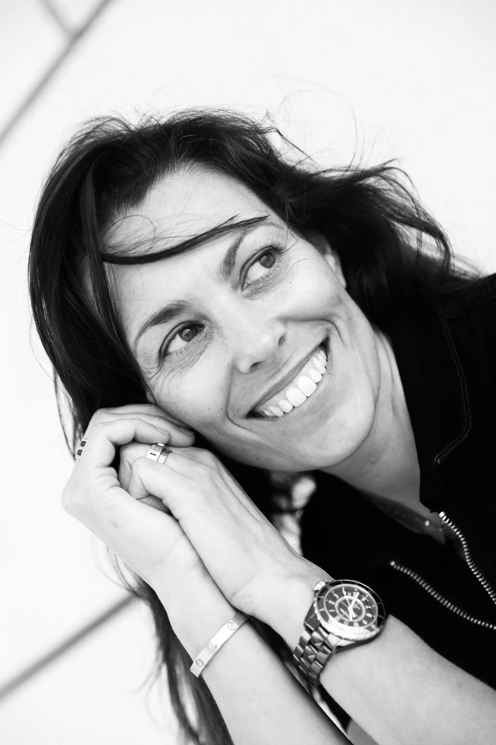 Black and white portrait of Cristina Gallice, smiling, hands against her cheek