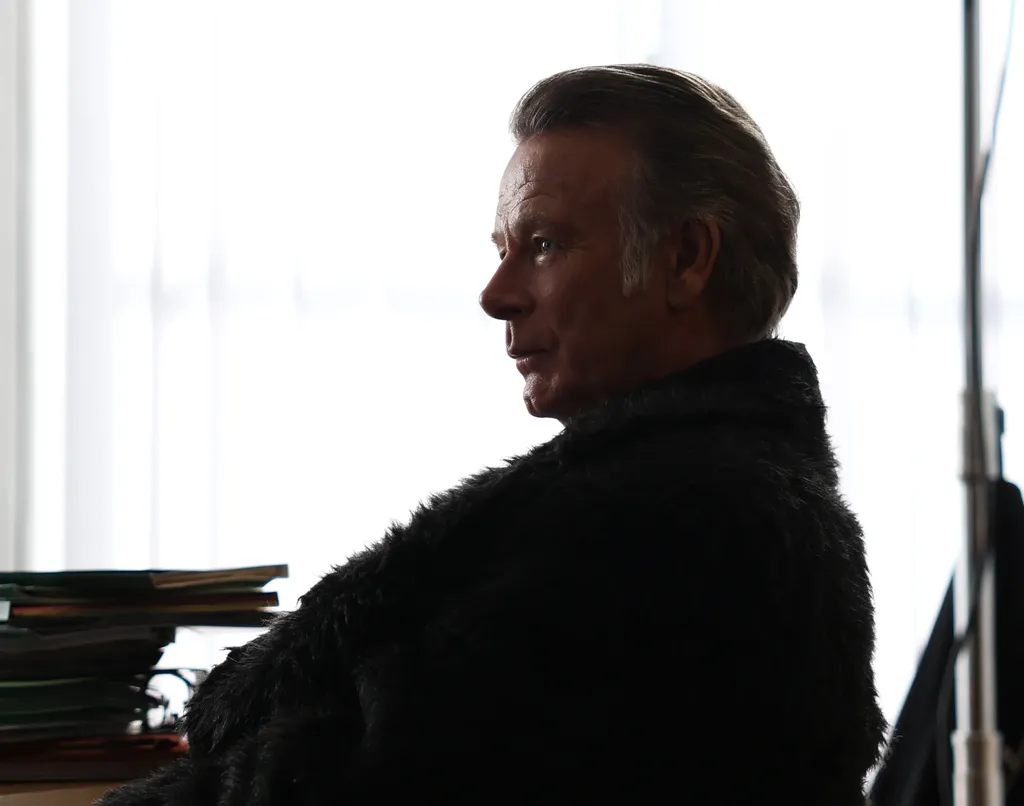 A man in a fur coat in profile, almost a silhouette against a bright window, colour.