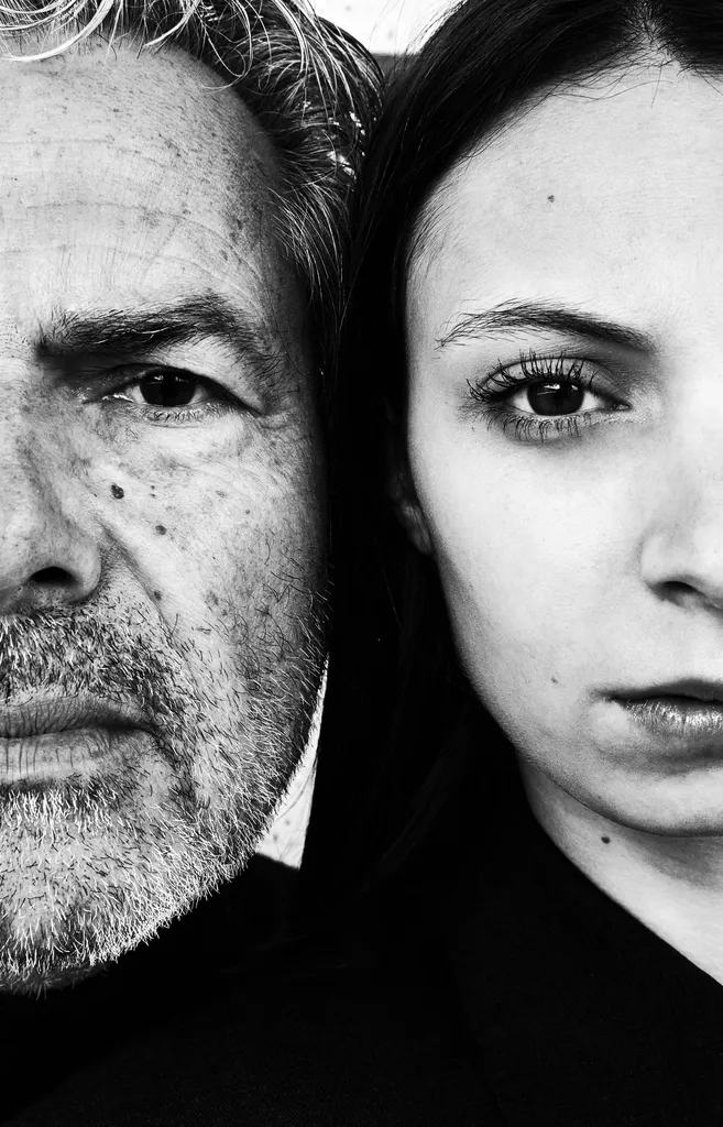 Black and white close-up of two faces cheek to cheek, an older man and a young woman, each cut by the frame.